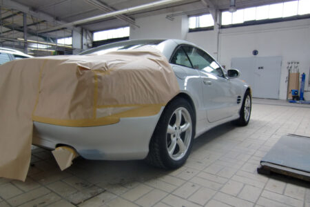 Silbernes Auto in der Werkstatt, Heck für Lackierung abgeklebt.
