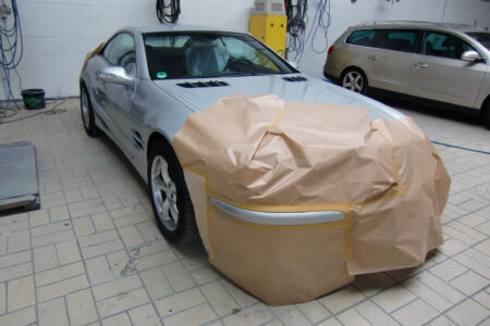 Silbernes Auto mit abgekleidetem Heck in der Werkstatt.